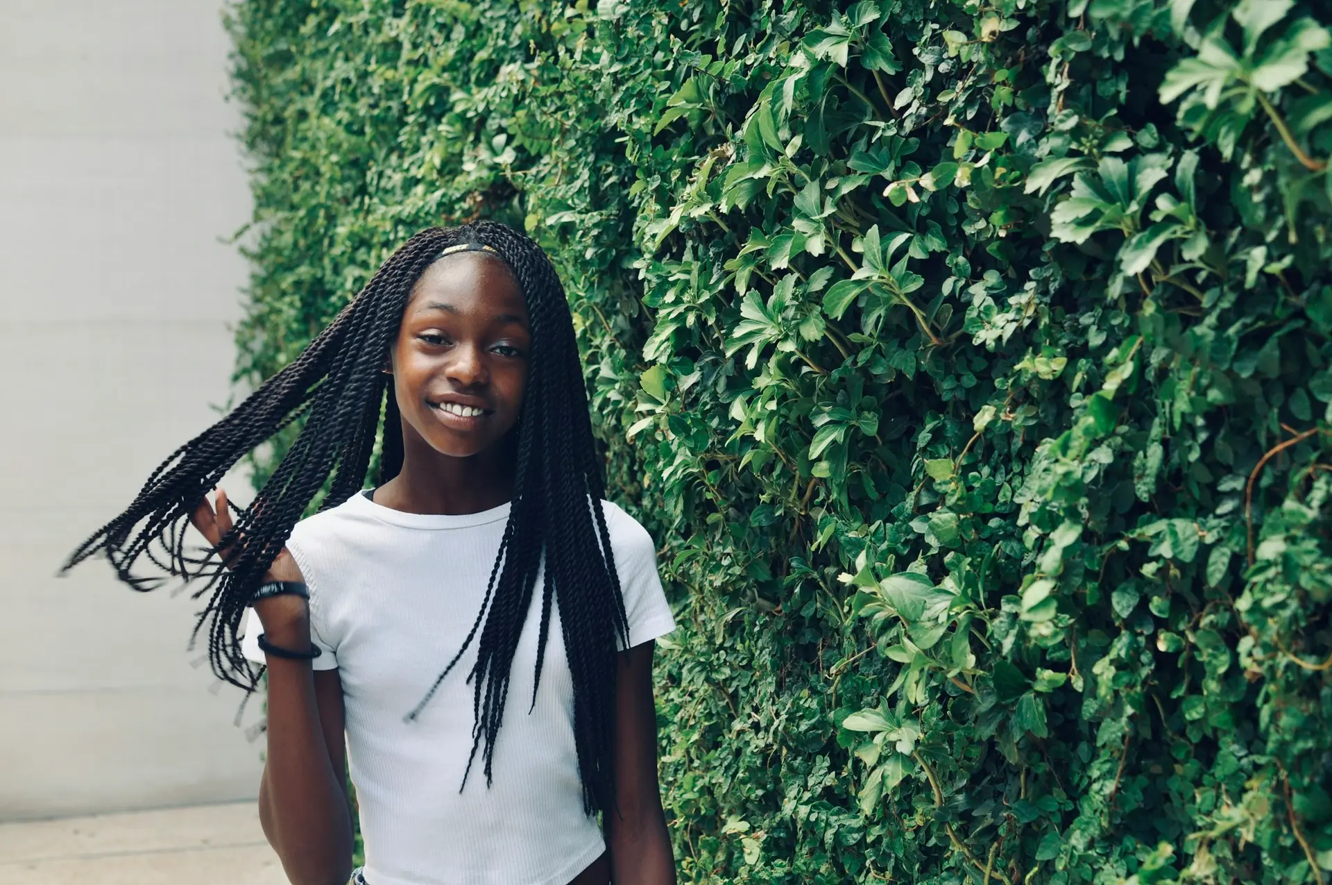 A smiling teenage girl in a white shirt standing outdoors