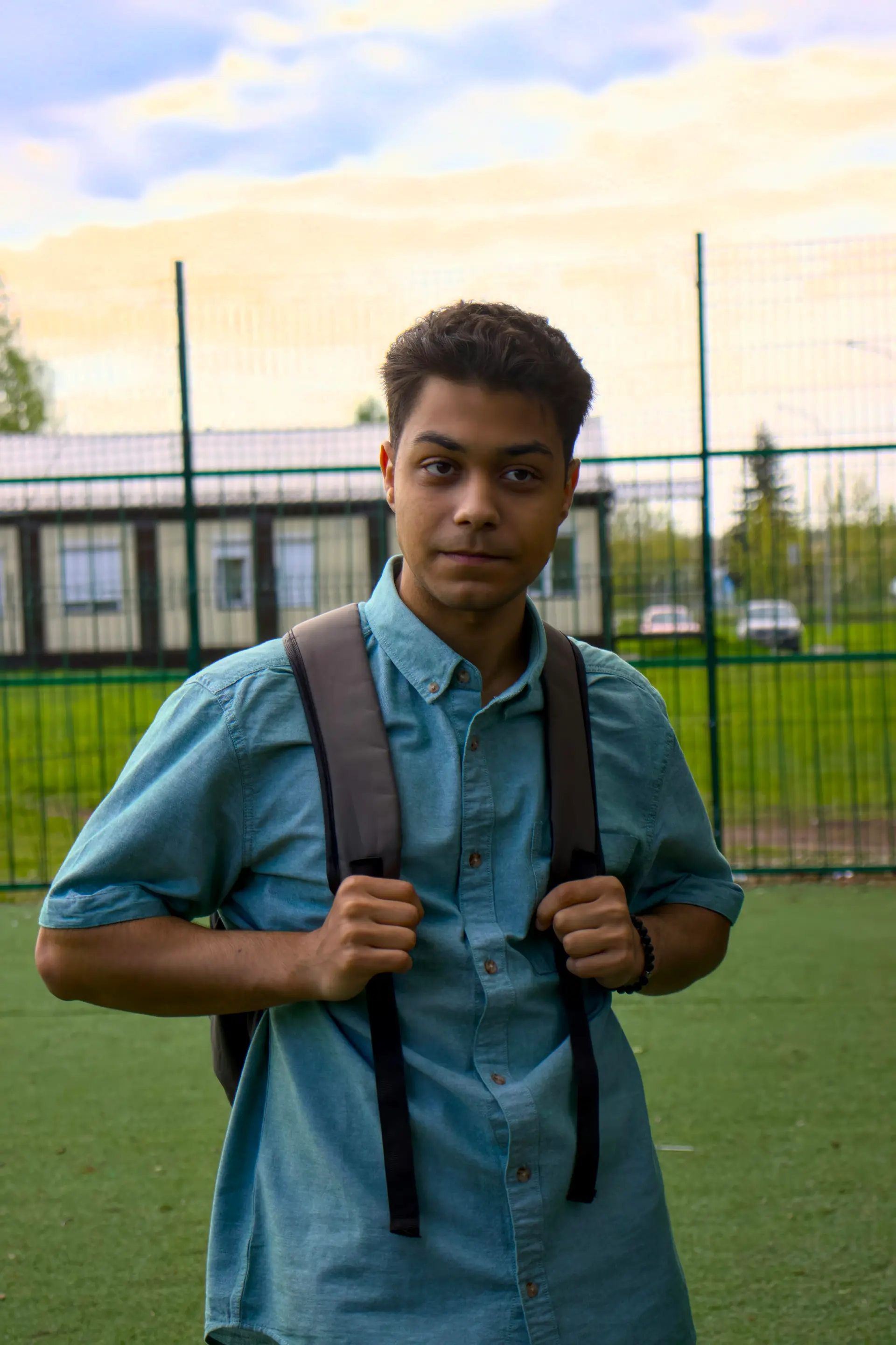 A high school student with a backpack standing outside a school