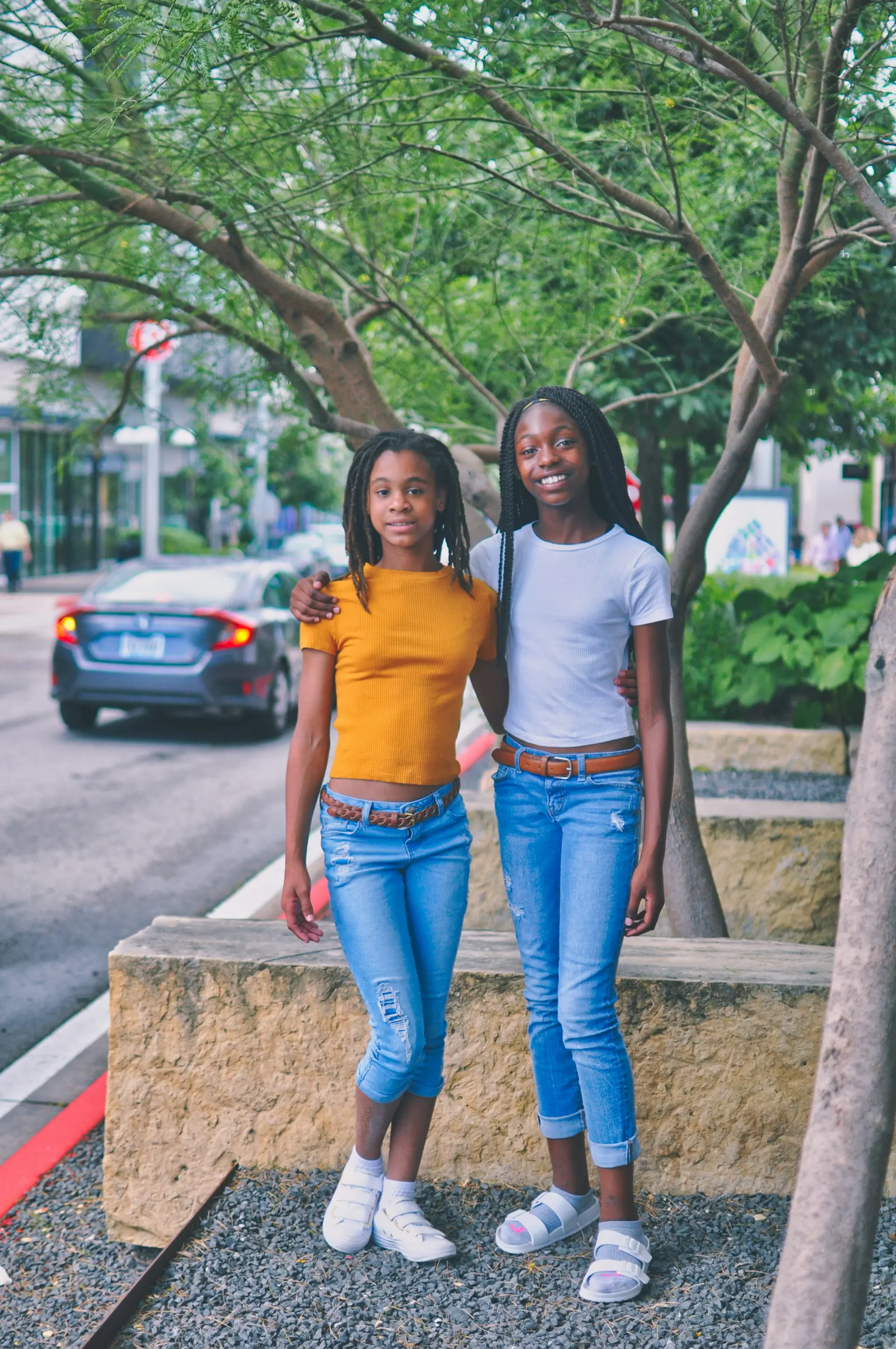 Two teenage girls walking together on a city sidewalk