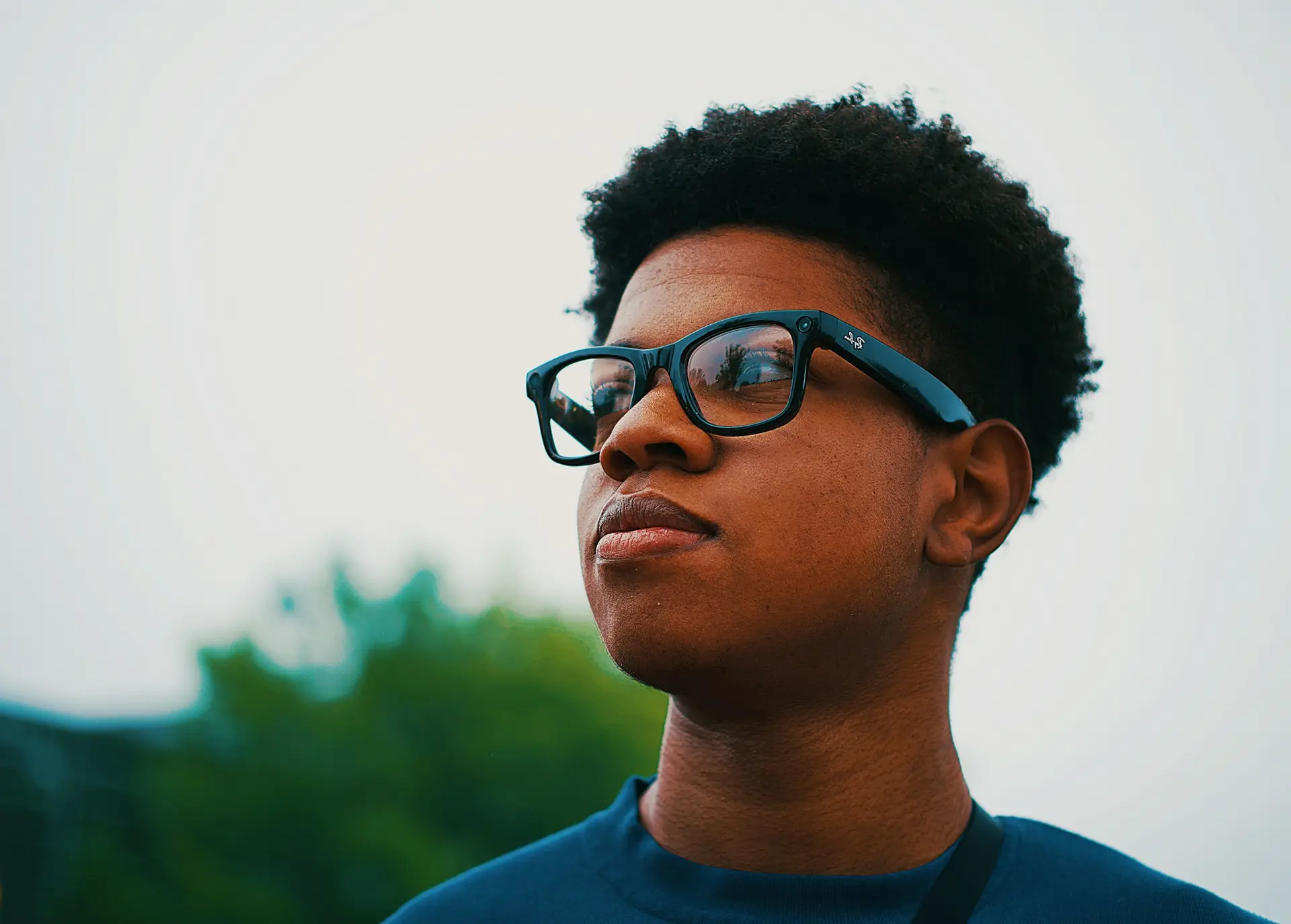 A teenage boy in glasses looking ahead with a confident expression