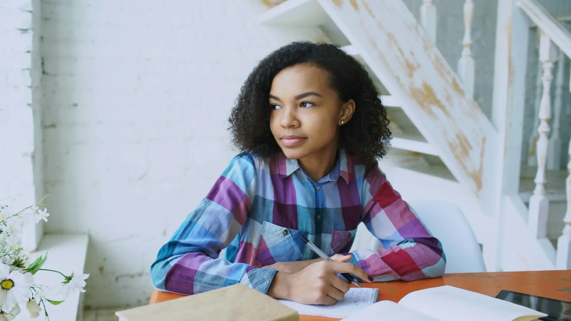 A teenage girl studying at a desk with notebooks open