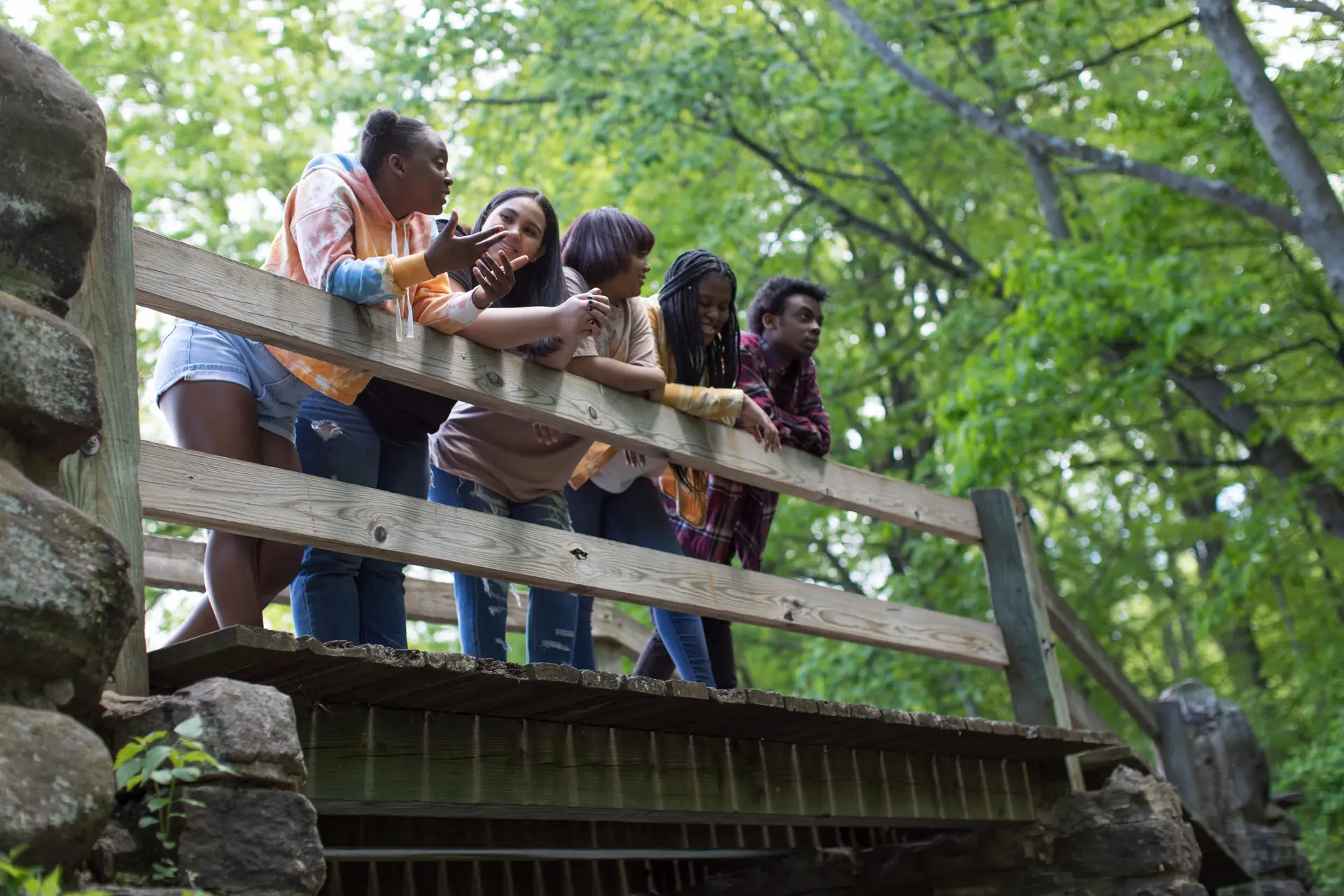 Teenagers gathered on a wooden footbridge during an outdoor experience