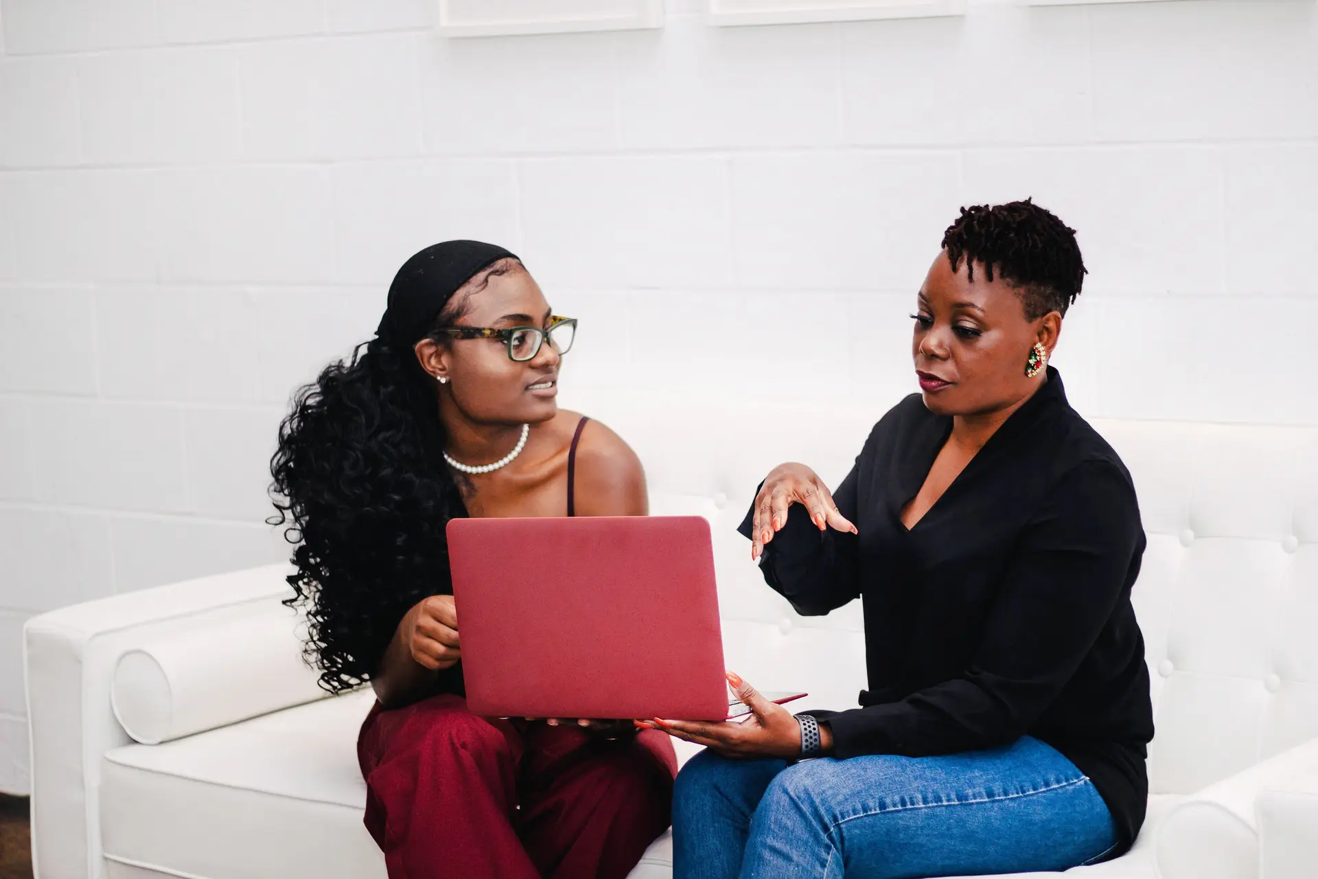 A professional woman mentoring a young woman with a laptop