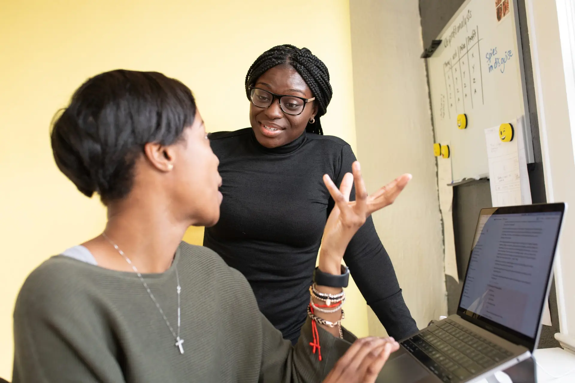 Two professionals collaborating at a laptop in a bright office
