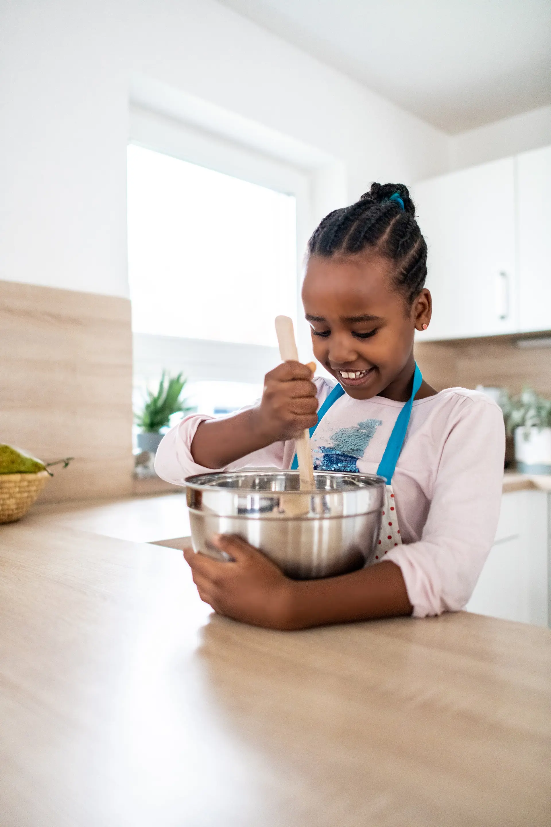 A smiling girl mixing ingredients in a bowl in a bright kitchen